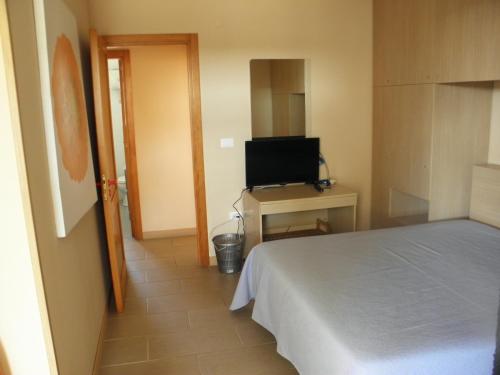 a bedroom with a bed and a desk with a television at Hotel Blue Sky - San Foca in San Foca