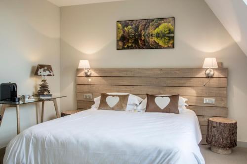 a bedroom with a white bed with a wooden headboard at Les Sagranières in Salers