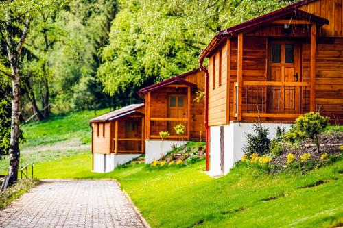 uma cabana de madeira numa colina relvada com um caminho em Letovisko Chobot - village resort em Kácov