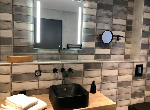 une salle de bains avec un lavabo noir et un miroir dans l'établissement Le Sagranier, à Salers