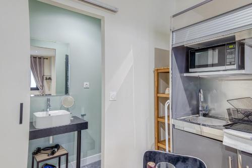 y baño con lavabo y microondas. en Appartements Emile Fourcand en Burdeos