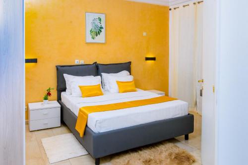 a bedroom with a large bed with orange walls and yellow pillows at RÉSIDENCE DOLCE VITA - BONANJO in Douala