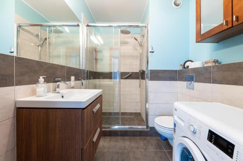 ein Badezimmer mit einer Dusche, einem Waschbecken und einer Waschmaschine in der Unterkunft Victus Apartamenty, Apartament Mewi Śpiew in Sopot