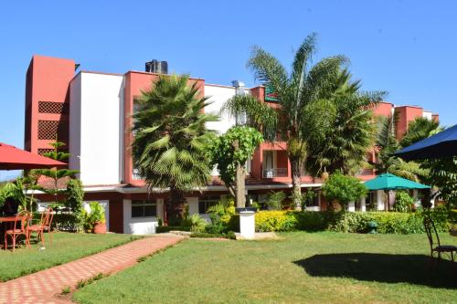 a building with palm trees in front of a yard at Meru Slopes Hotel in Meru