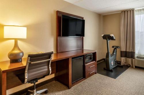 a hotel room with a desk with a television and a chair at Comfort Suites Manassas Battlefield Park in Manassas