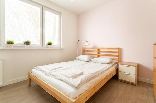 a white bedroom with a bed and a window at Victus Apartamenty, Apartament Malta in Sopot