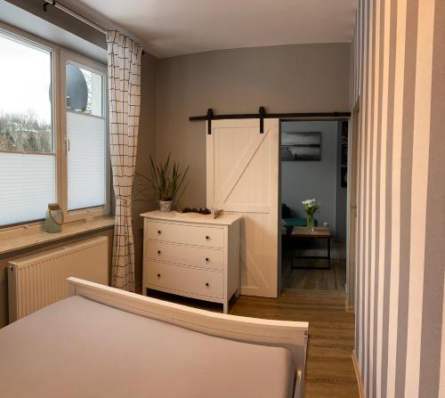 um quarto com uma cama, uma cómoda e uma janela em Apartamenty u Rybki em Krynica Zdrój