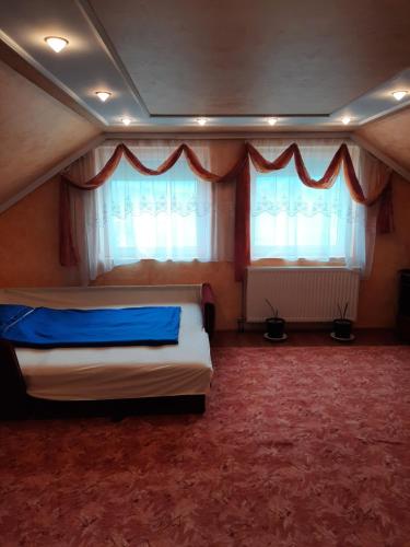 a bedroom with two beds and two windows at Fűvészkert in Lengyeltóti