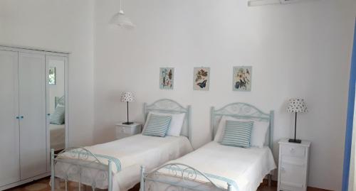 2 camas en un dormitorio con paredes blancas en Villa gli Ulivi con ampio giardino ed ogni comfort a pochi passi dal mare vicino Gallipoli, en Torre Suda