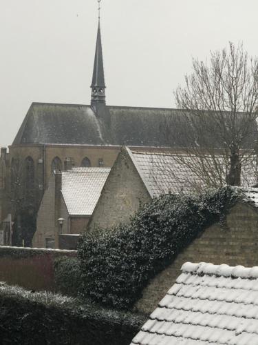 a church with snow covered roofs in front of a building at B&B 't Withuis in Diksmuide