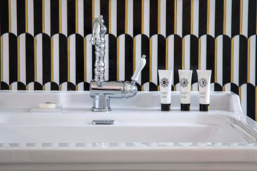 a bathroom sink with a faucet and four toothbrushes at Hôtel Aiglon in Paris