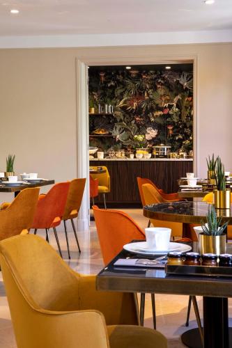 a restaurant with tables and chairs and a large mural at Hôtel Aiglon in Paris