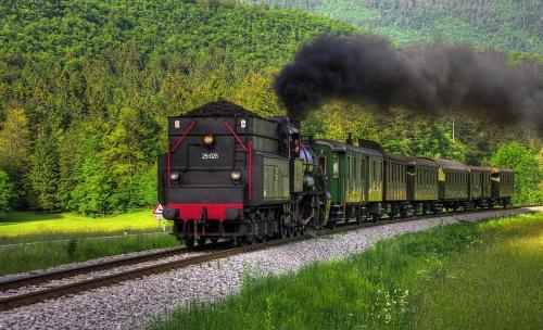 a train is coming down the tracks with black smoke at Hotel Tripič, restaurant and pizzeria in Bohinj