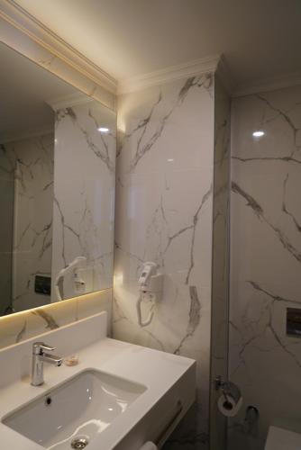a white bathroom with a sink and a shower at Doğruer Hotel & Spa in Muğla