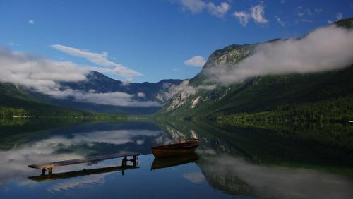 a boat sitting next to a dock on a lake at Hotel Tripič, restaurant and pizzeria in Bohinj