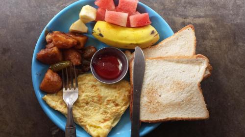 a blue plate of breakfast food with toast and fruit at Hotel National Park Sauraha- Homely Stay and Peaceful Location with Jungle Safari arrangements in Sauraha