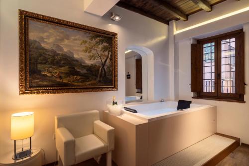 a bathroom with a tub and a chair and a painting at Gigli D'Oro Suite in Rome
