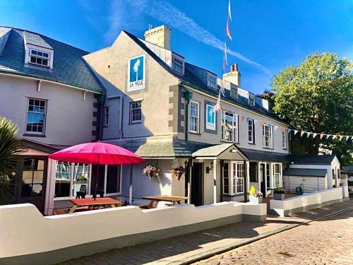 a large building with a red umbrella in front of it at La Ville Hotel in Alderney