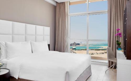 um quarto com uma grande cama branca e uma grande janela em Staybridge Suites - Doha Lusail, an IHG Hotel em Doha