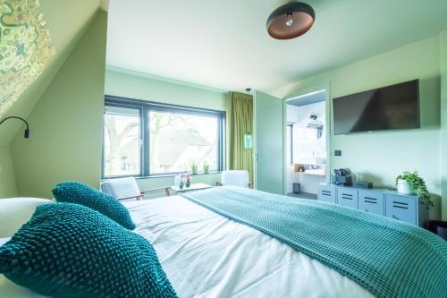a bedroom with a large white bed with blue pillows at LUDIEK eten en slapen in Havelte