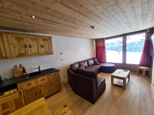 a living room with a leather couch and a table at Chalet Le Granitic in Les Menuires