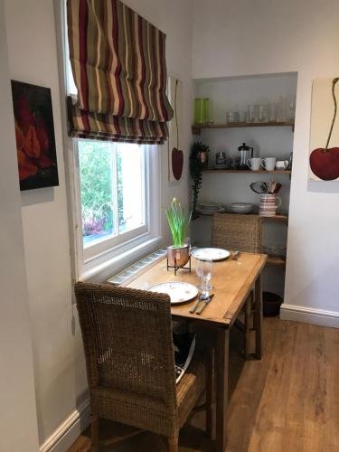 a dining room table with chairs and a window at Claremont Coach House in Frensham