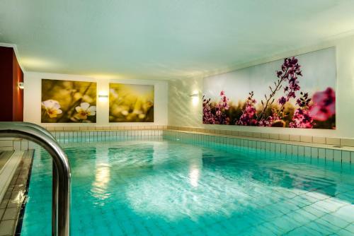 ein Pool mit zwei Blumenmalereien an den Wänden in der Unterkunft Hotel Reethüüs in Kampen