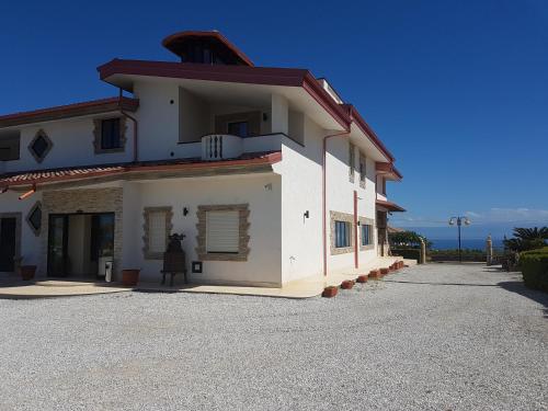 a large white building with the ocean in the background at Hotel La Campagnola in Capo Vaticano