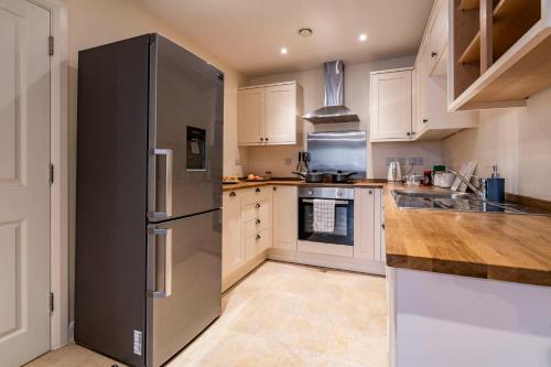 uma cozinha com um frigorífico de aço inoxidável e armários brancos em MPL Apartments - Queens Broadway F3 em Watford