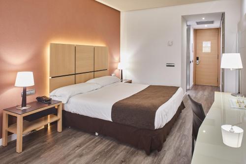 ein Hotelzimmer mit einem großen Bett und einem Schreibtisch in der Unterkunft Silken Puerta Valencia in Valencia