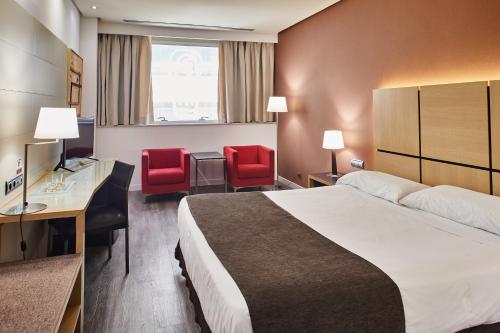 um quarto de hotel com uma cama e duas cadeiras vermelhas em Silken Puerta Valencia em Valência