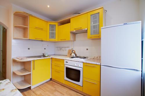 a kitchen with yellow cabinets and a refrigerator at Vilenskaja 25 in Maladzyechna