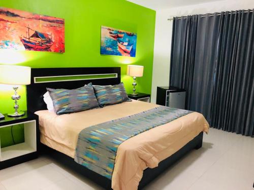 a bedroom with a bed with a green wall at Dpravia Hotel SRL in Baní