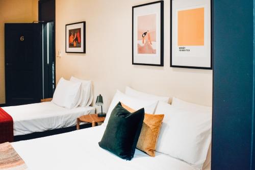 利斯莫尔The Sherwood Hotel的酒店客房设有两张床,墙上挂有照片
