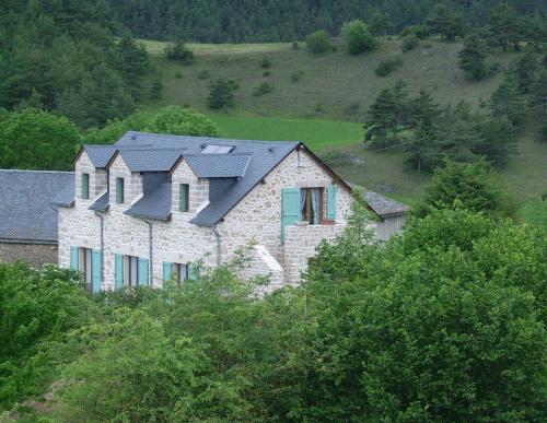 una gran casa de piedra con cuatro techos en una colina en Chez Louis chambres d'hôtes à la ferme, en La Canourgue