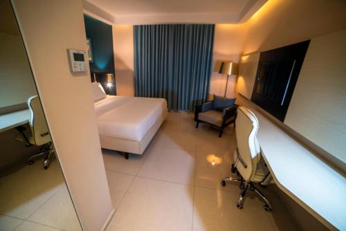 a hotel room with a bed and a chair at Best Western Plus Soaho Douala Airport in Douala