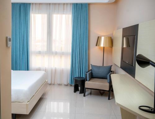 a hotel room with a bed and a chair and a window at Best Western Plus Soaho Douala Airport in Douala