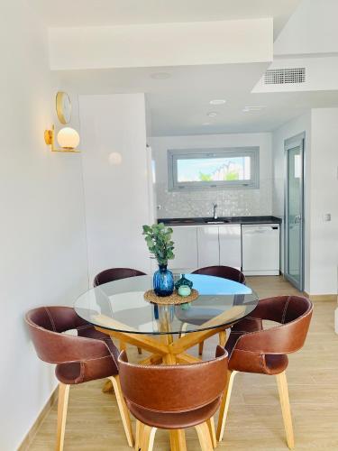 a dining room with a glass table and leather chairs at Apartamento con solarium Villa Amalia in Torrevieja
