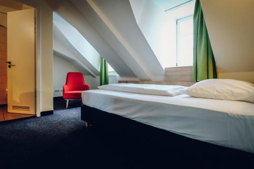 a bedroom with a bed and a red chair at Hotel Europa in Bamberg