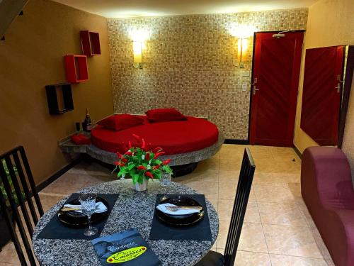 a bedroom with a red bed and two tables and chairs at Motel Emoções (Adults Only) in Fortaleza