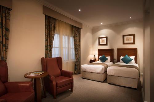 a hotel room with two beds and a chair at The Royal Horseguards Hotel, London in London