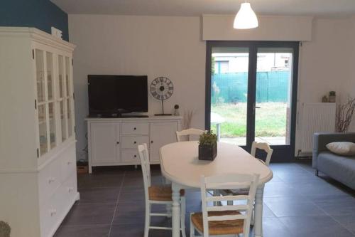un salon avec une table et des chaises blanches dans l'établissement Maison de plain pied avec jardin, à Bruay-la-Buissière
