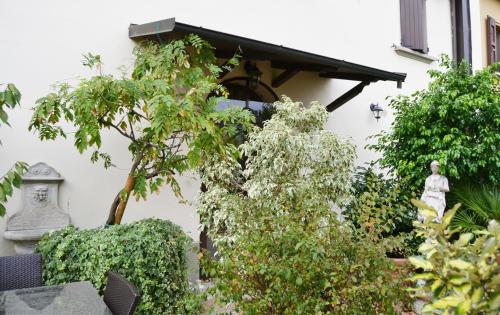 un jardin en face d'une maison blanche avec des plantes dans l'établissement Casa Nives, à San Pietro in Casale