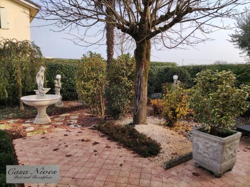 un giardino con una statua e un albero di Casa Nives a San Pietro in Casale