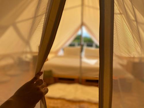 a persons hand holding a wooden pole in a tent at Tanoshi Glamping In Khao Sok in Khao Sok