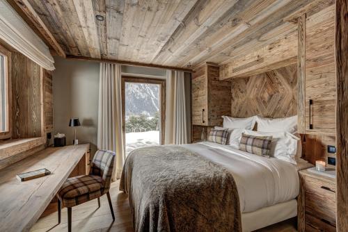a bedroom with a bed and a desk and a window at Le Hameau des Nants in Chamonix-Mont-Blanc