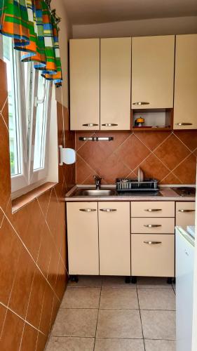 cocina con armarios blancos, fregadero y ventana en Apartments Maša, en Budva