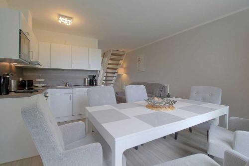 eine Küche und ein Esszimmer mit einem weißen Tisch und Stühlen in der Unterkunft KW4b Haus Cati in Dorum Neufeld