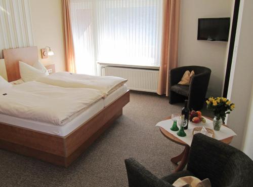 um quarto de hotel com uma cama e uma cadeira em Pension Haus Waldfrieden, MeineCardPlus inklusive em Willingen