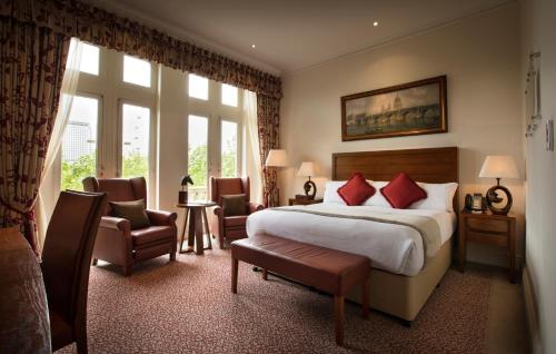 a hotel room with a bed and chairs and a window at The Royal Horseguards Hotel, London in London